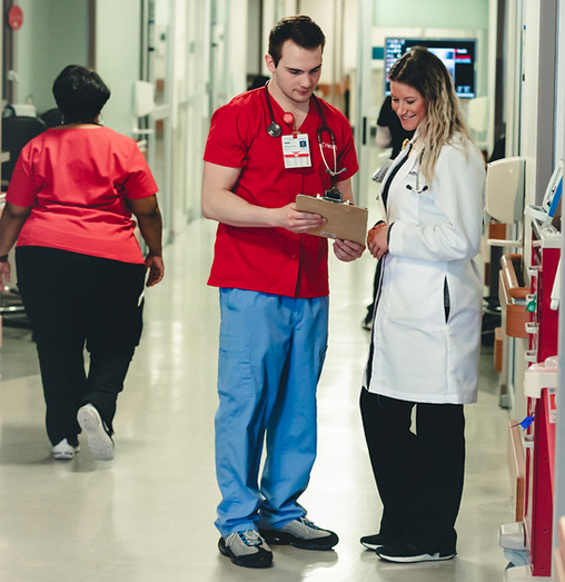  	A male nurse consults with a female doctor in the hospital hallway.